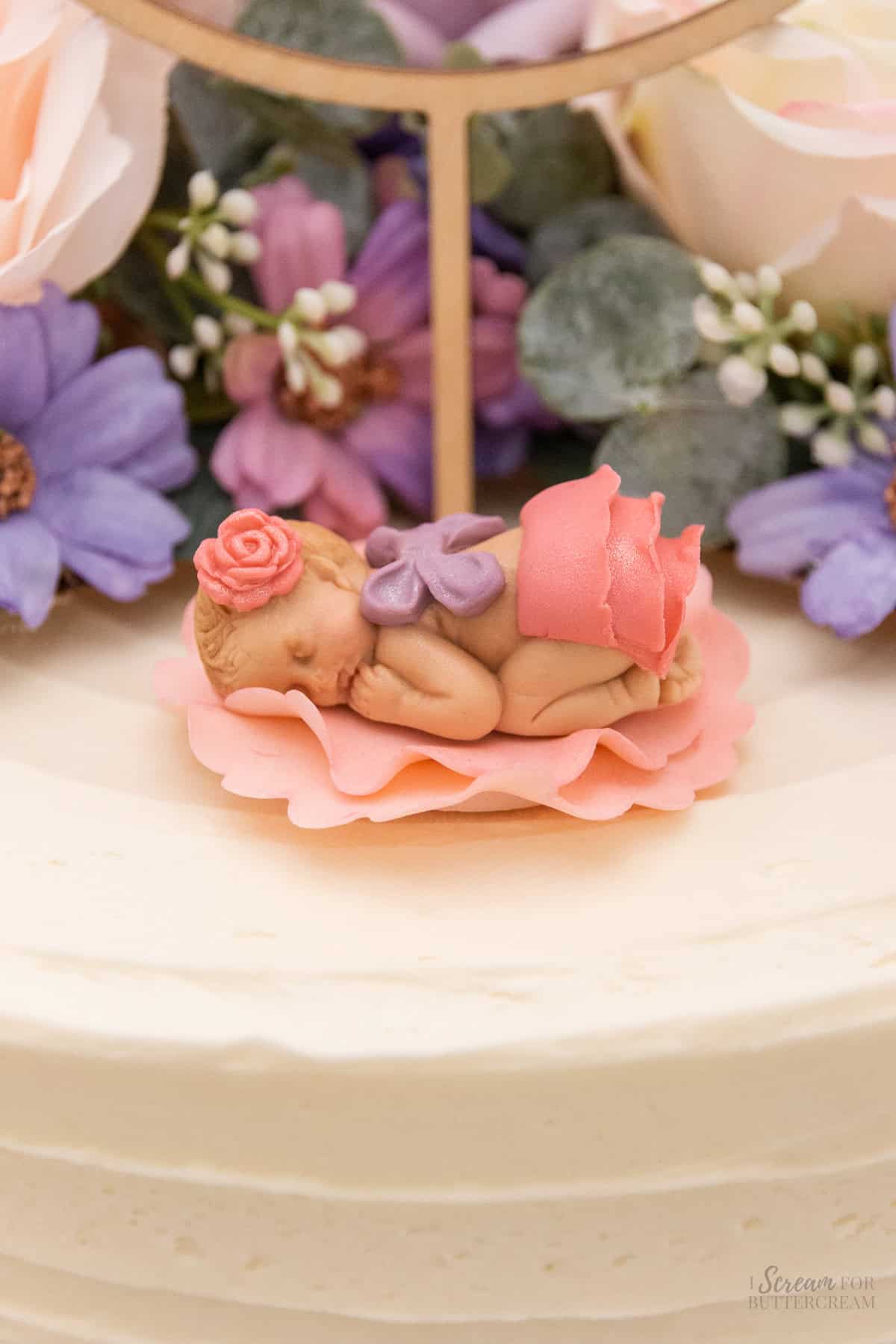 Fondant decorated baby on the top of the cake.