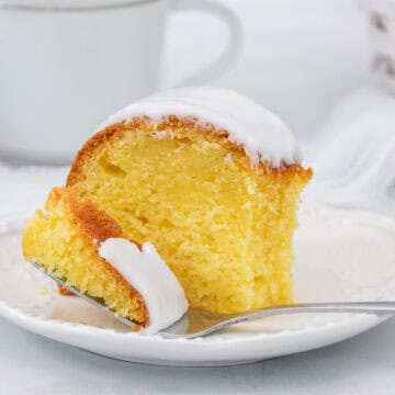 Close up of lemon cream cheese cake with fork on a white plate.