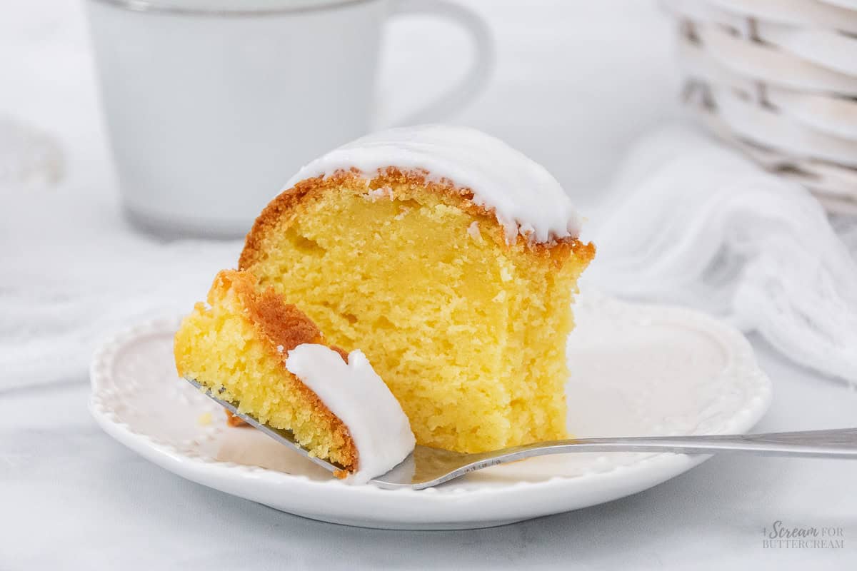 Close up of lemon cream cheese cake with fork on a white plate.