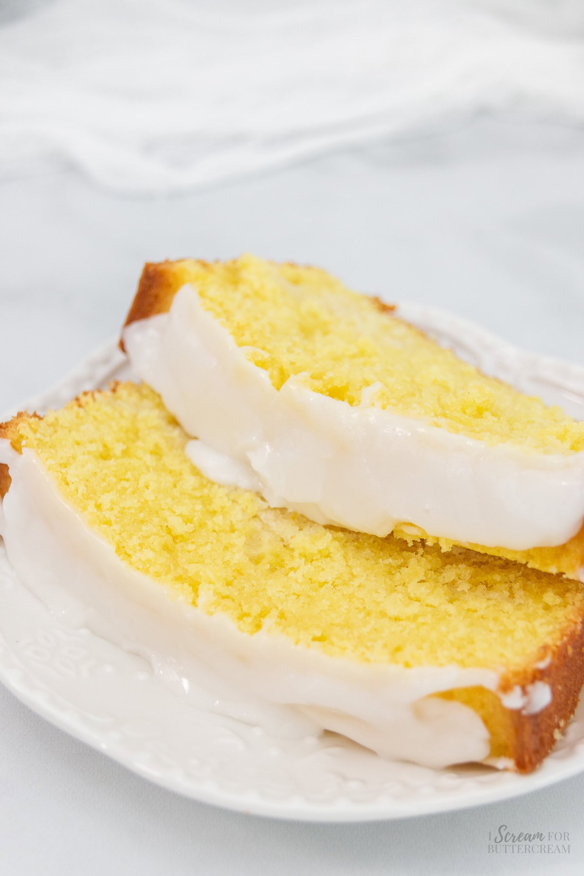 Close up image of slices of lemon loaf cake with glaze on a white plate.