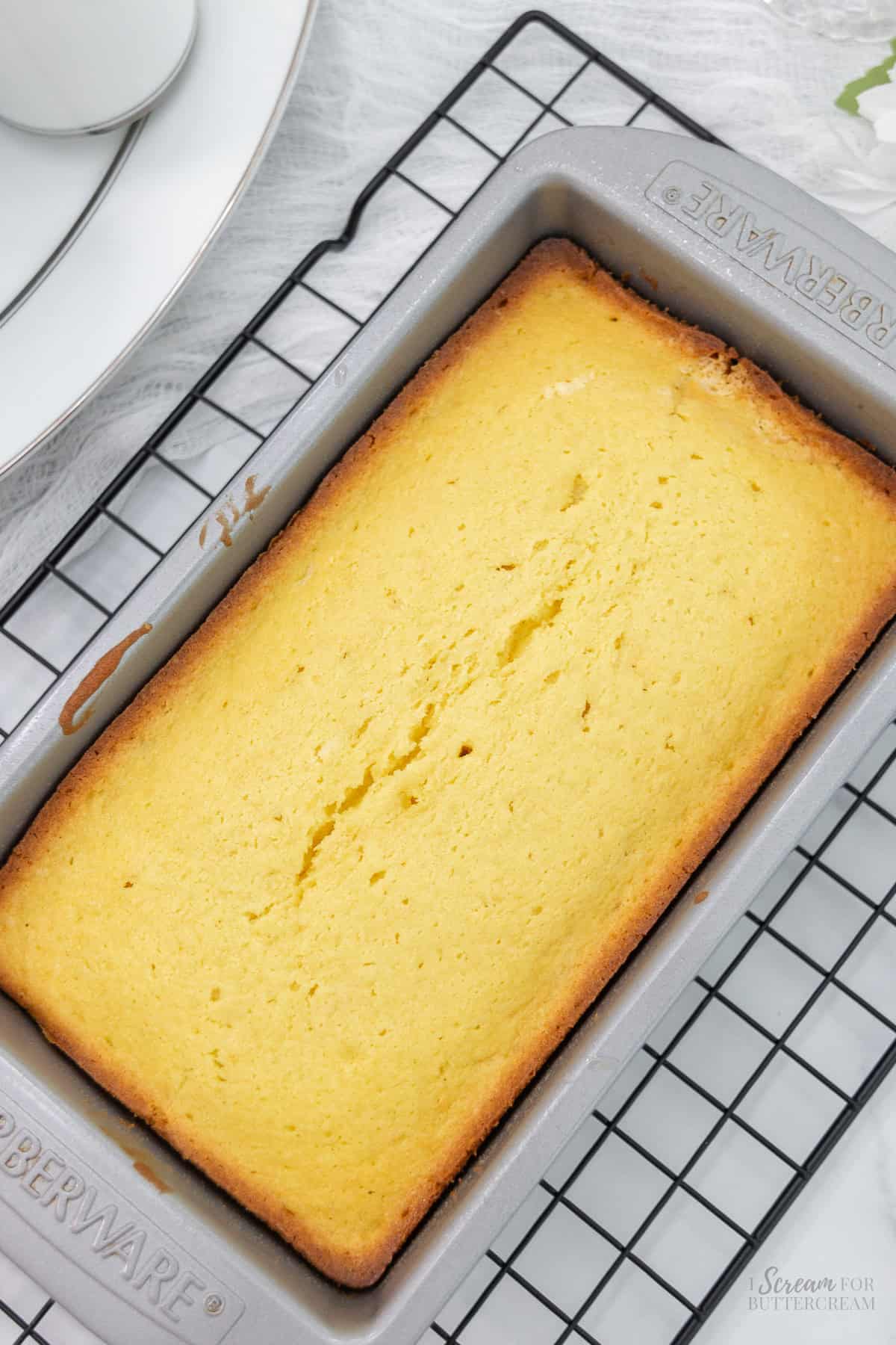 Top down look of baked lemon bread in a loaf pan on a cooling rack.