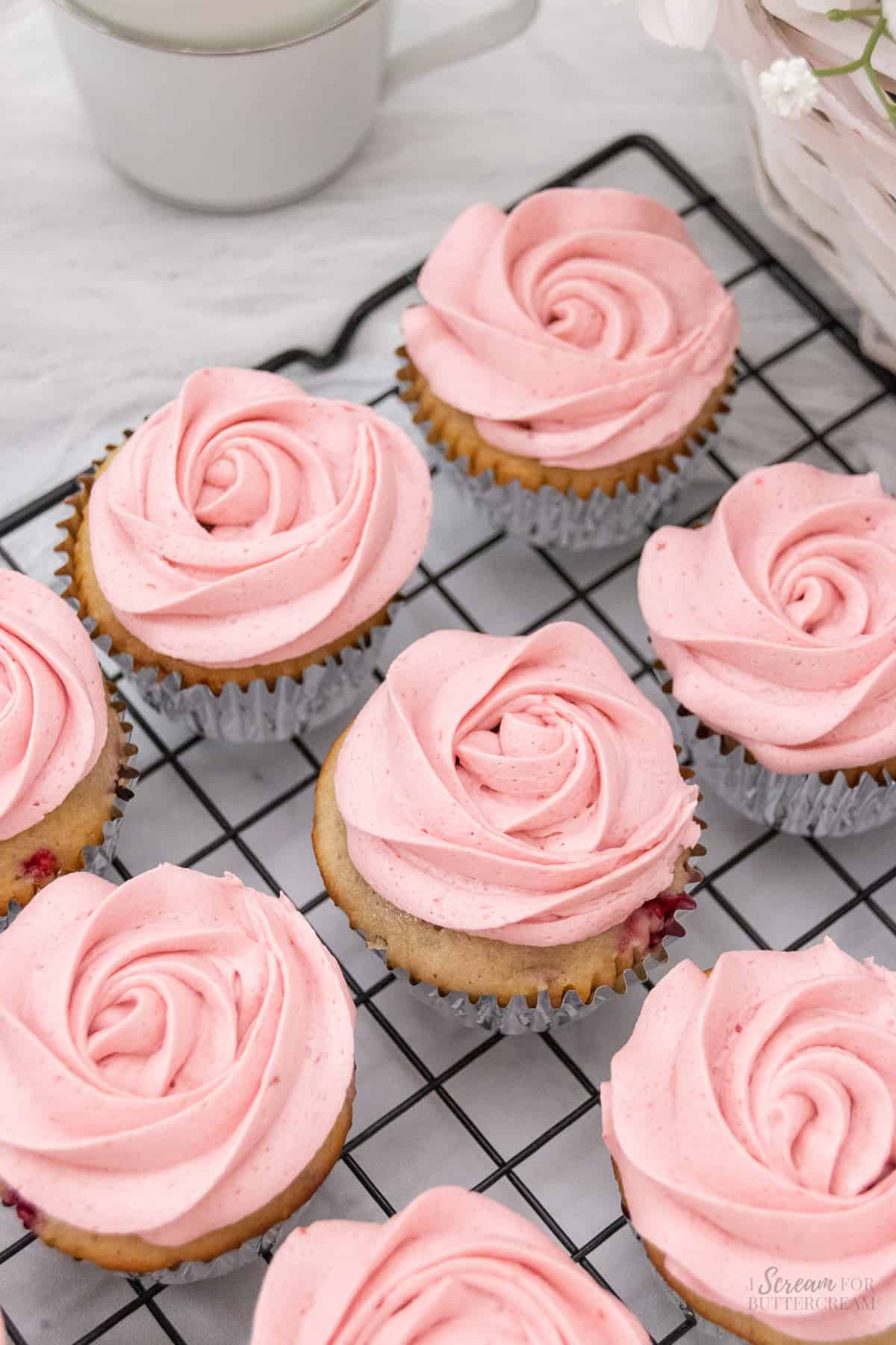 Top view of iced raspberry cupcakes on a cooling rack.