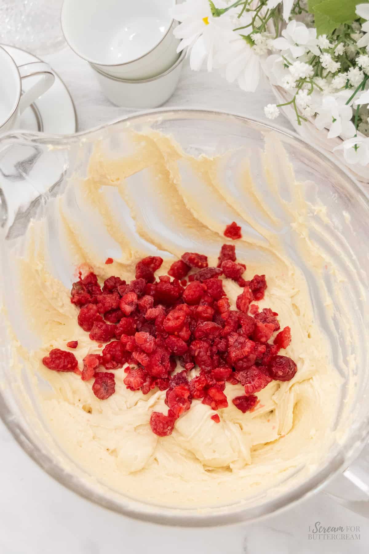 Raspberries added to cake batter in a glass mixing bowl.