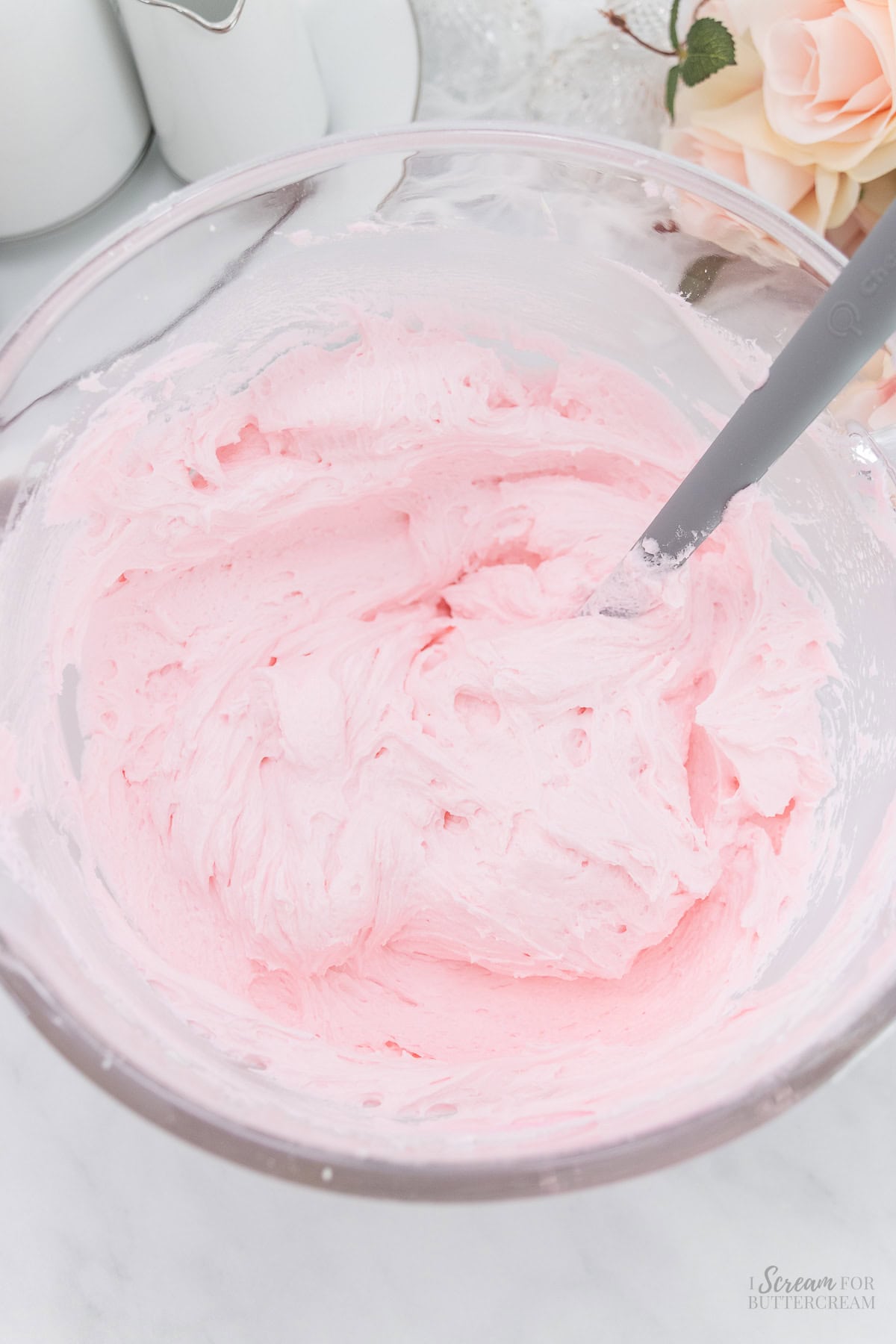 Pink buttercream mixed in a glass bowl.