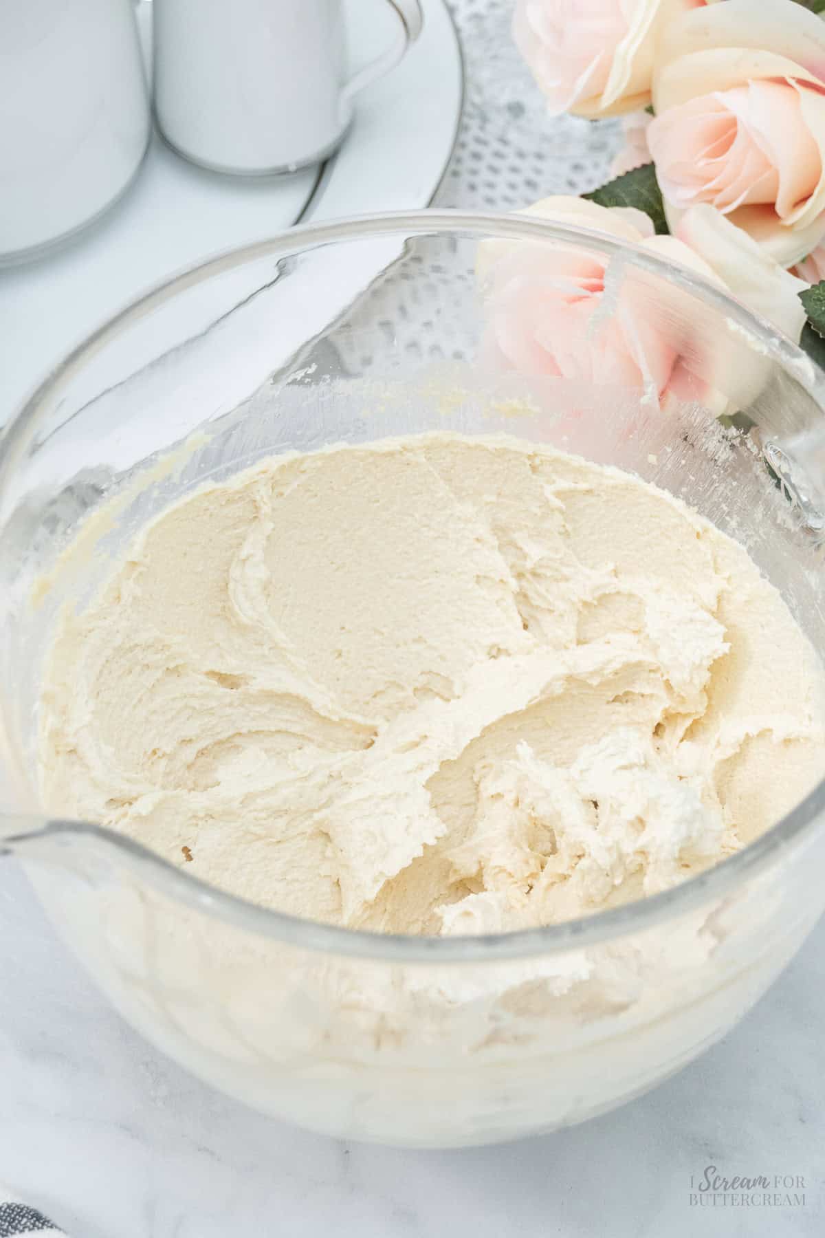 A glass mixing bowl filled with creamy, whipped cake batter, ready to be baked.