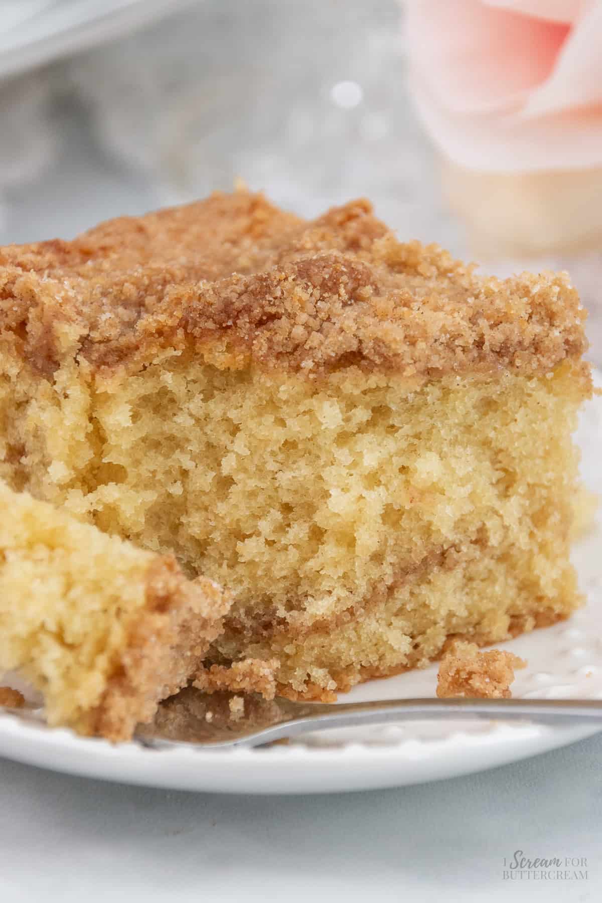 A close-up of a slice of buttermilk coffee cake with a crumbly cinnamon-sugar topping, highlighting its moist texture and tender crumb.