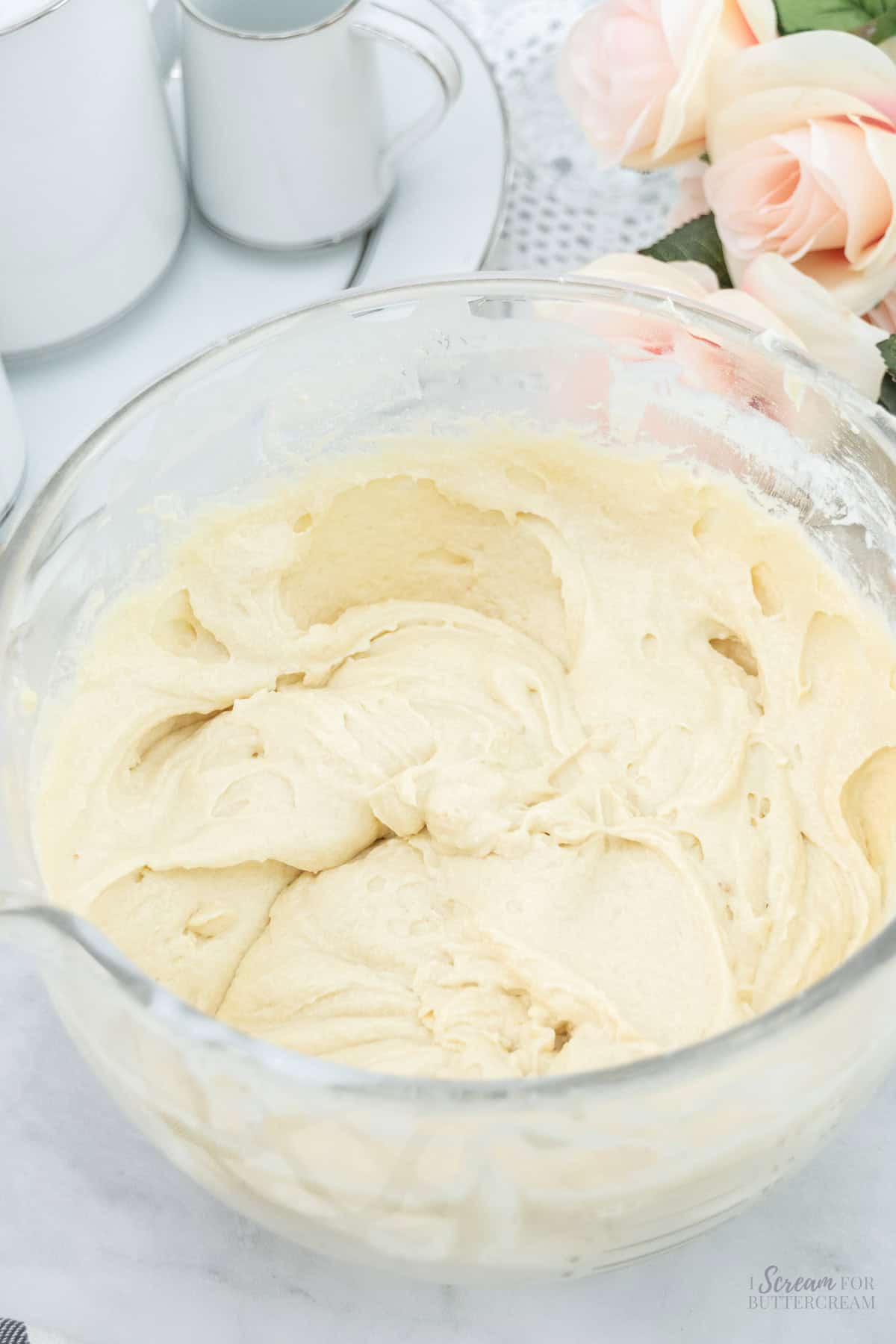 A glass bowl filled with smooth, creamy cake batter, ready to be poured into a baking pan.