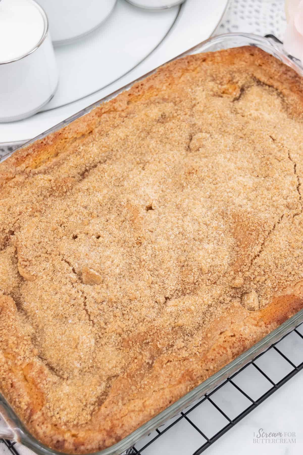 A freshly baked buttermilk coffee cake in a glass baking dish, topped with a golden cinnamon-sugar crust.