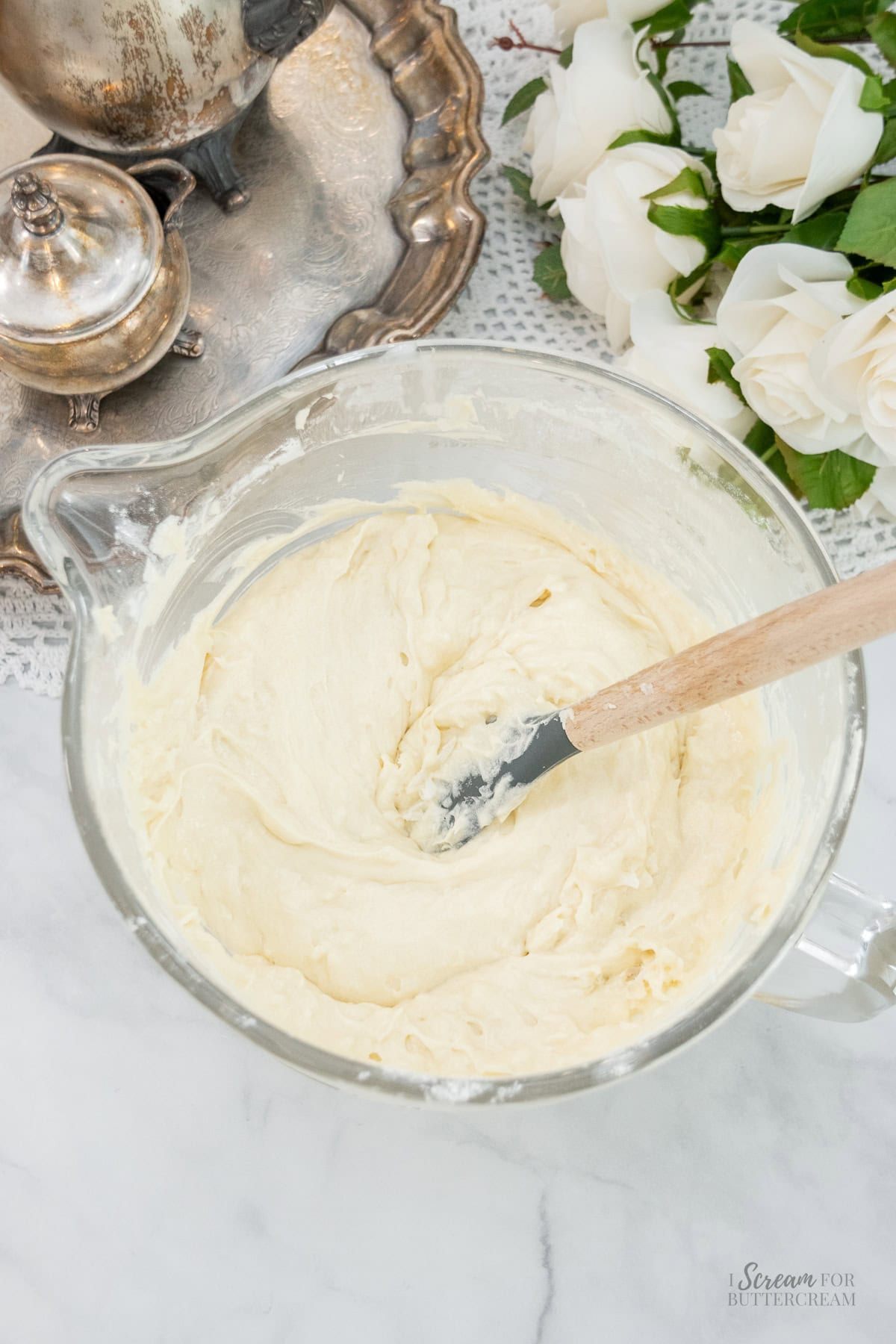 Thick coconut pound cake batter in a glass bowl with a rubber spatula ready for pouring.