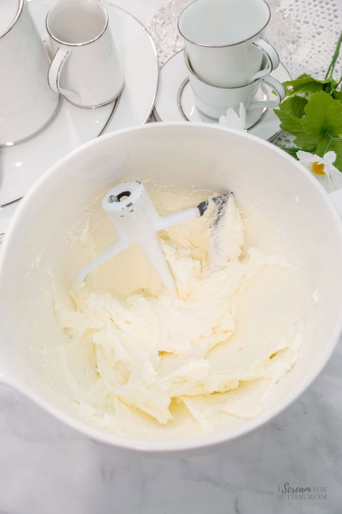 Creamed butter and sugar mixture in a white mixing bowl with a paddle attachment.