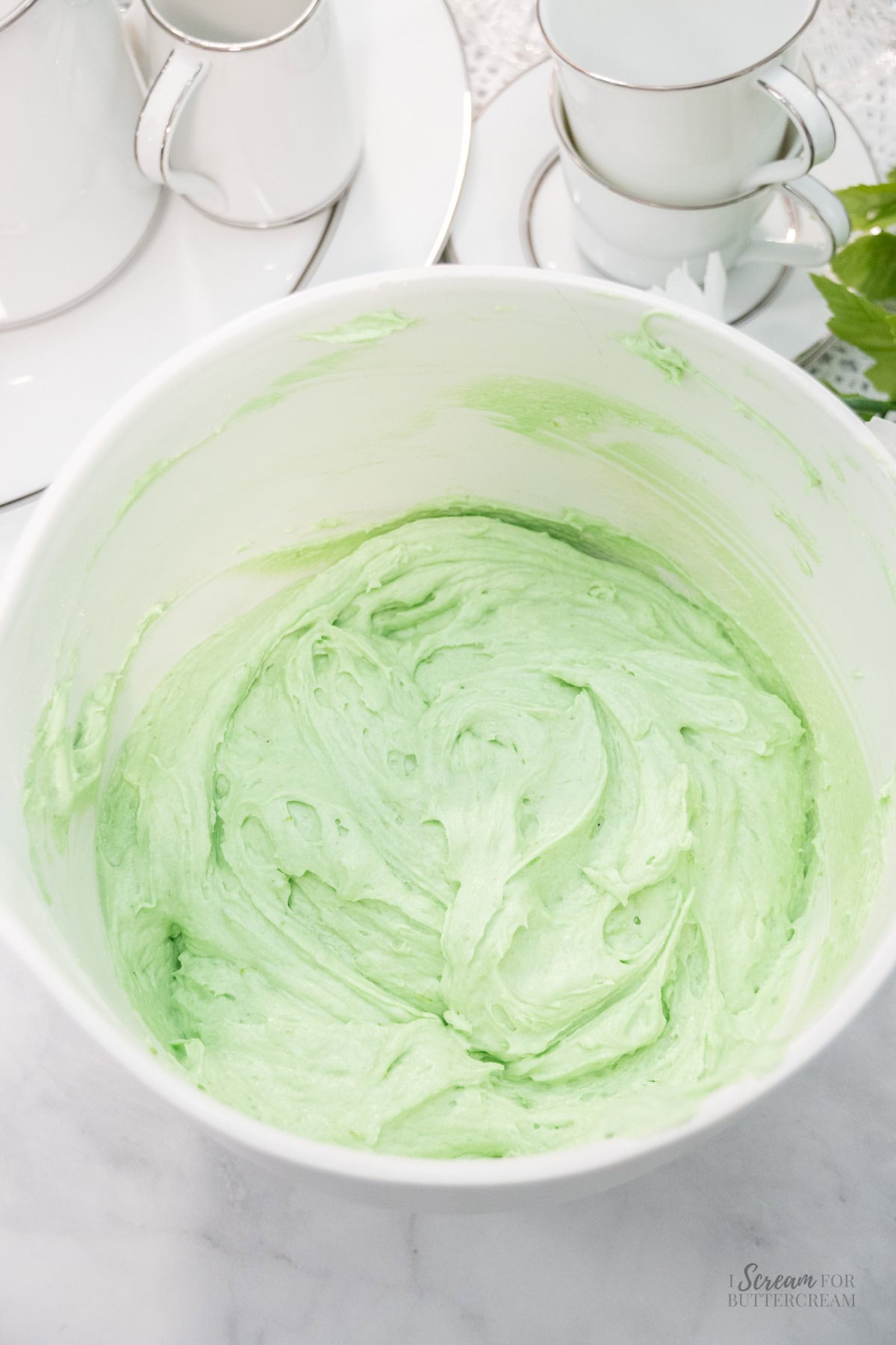 Fluffy, light green key lime cake batter swirled in a white mixing bowl.