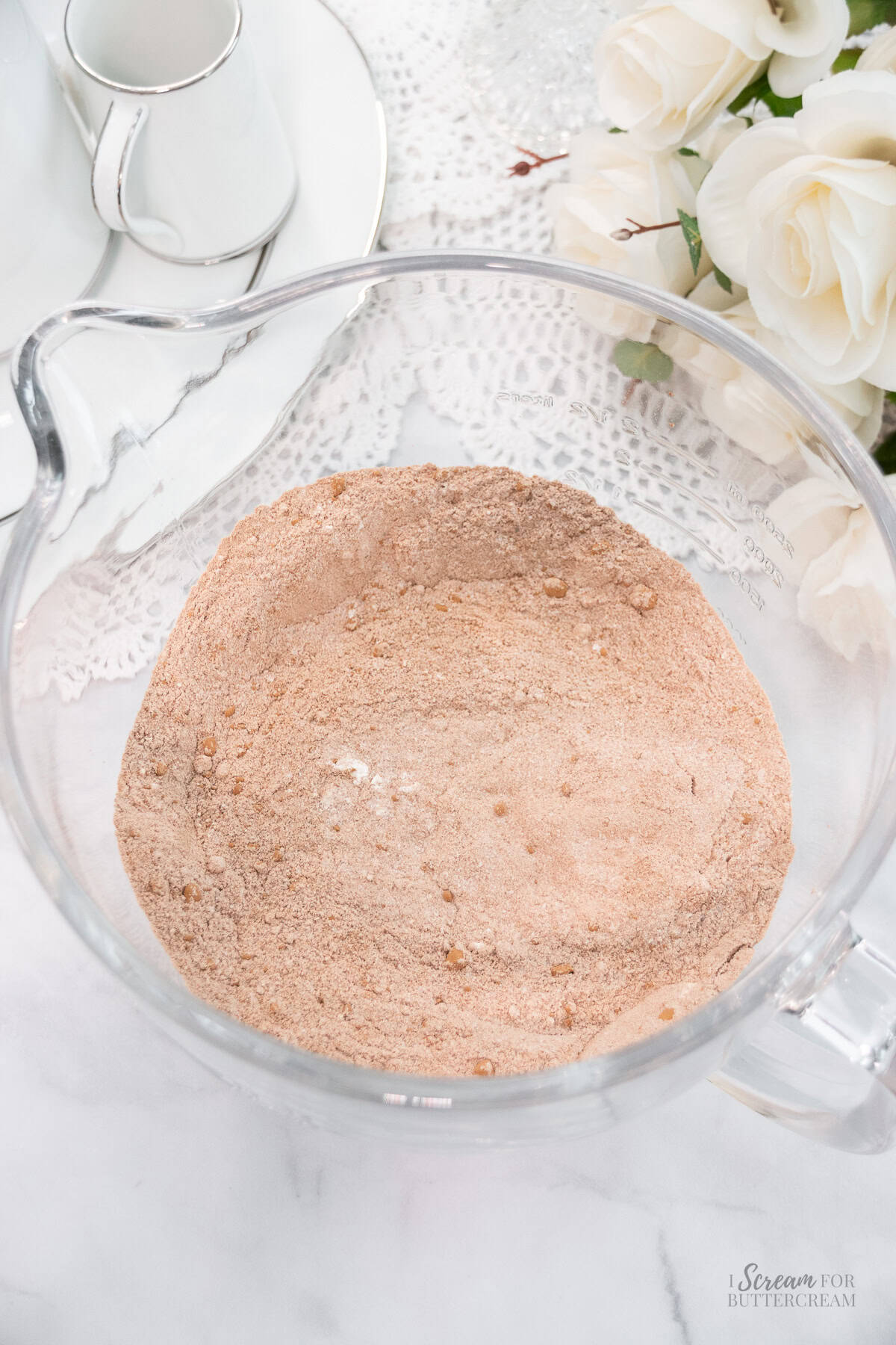 Dry chocolate cake ingredients in a clear glass mixing bowl.