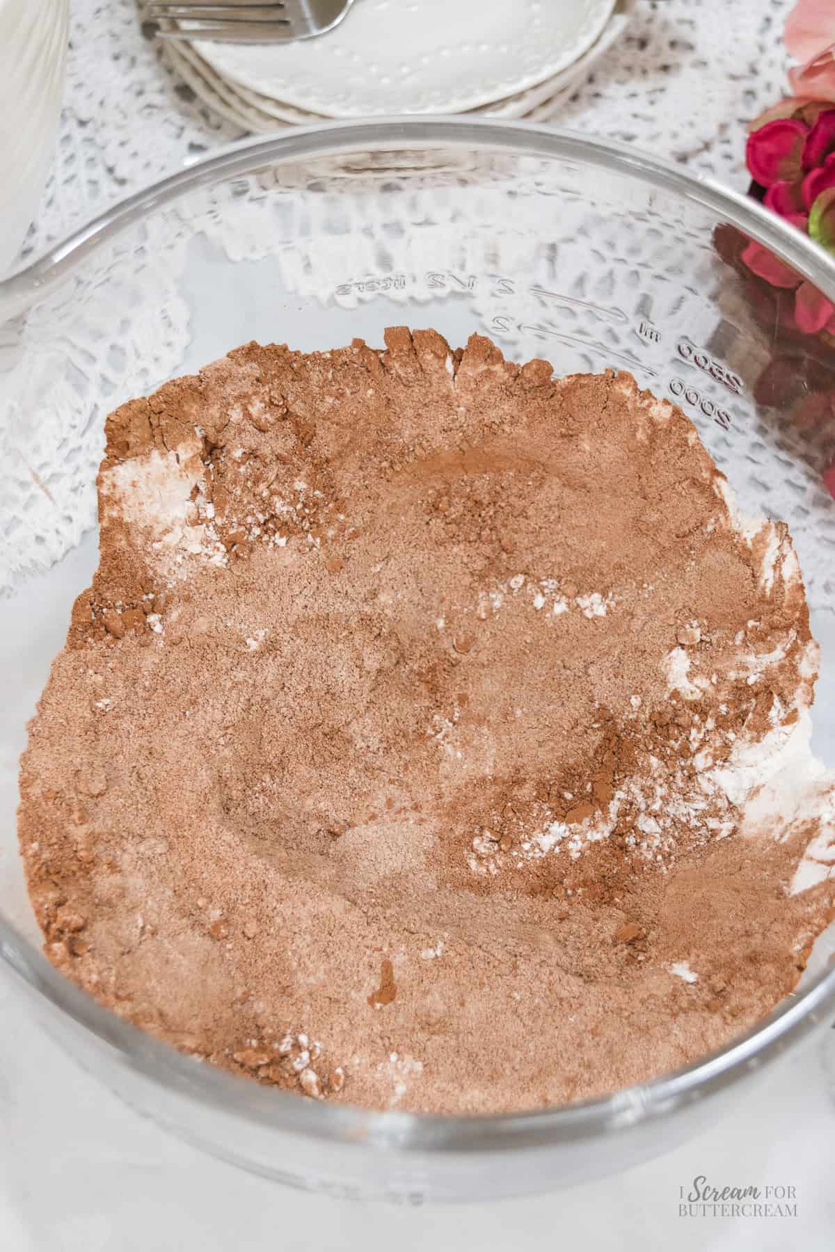 Dry ingredients for chocolate Nutella cake, including flour and cocoa powder, combined in a large glass mixing bowl.