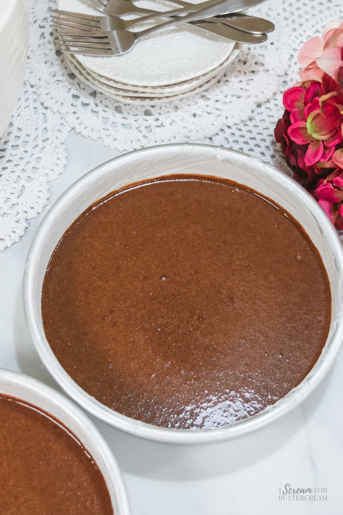 Chocolate Nutella cake batter poured into prepared round cake pans before baking.