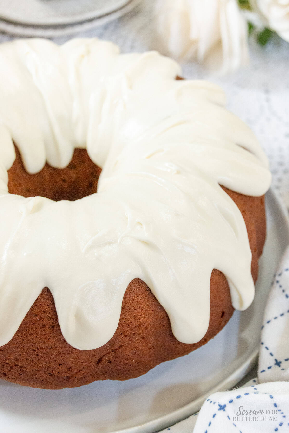 Close-up of pumpkin spice Bundt cake topped with thick, creamy white cream cheese glaze dripping down the golden-brown sides.